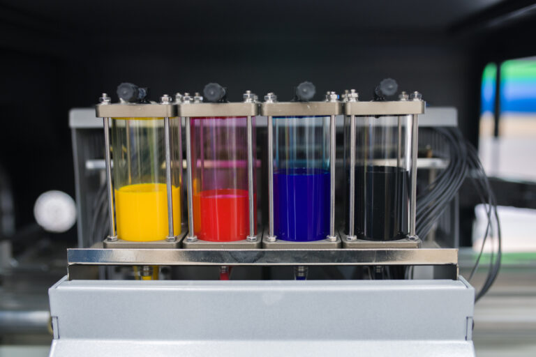 Close-up of colorful plotter ink tanks used for printing machine in printing shop of publishing company